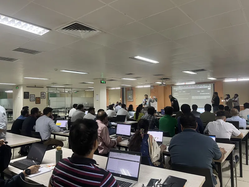 A packed training room in Lahore, staff at laptops, seen from the back